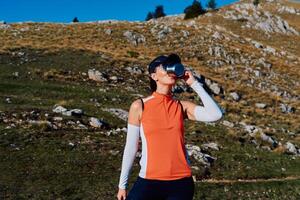 A female hiker enjoys a warm cup of tea while resting after a challenging mountain climb.A woman hiker takes a peaceful break, sipping tea and enjoying the view after a strenuous mountain climb photo
