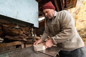 Carpenter Cutting Wood with a Bandsaw in a Rustic Workshop photo