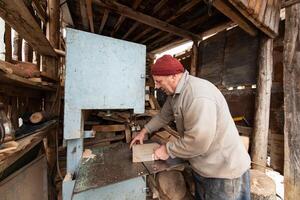 Carpenter Cutting Wood with a Bandsaw in a Rustic Workshop photo