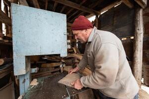 Carpenter Cutting Wood with a Bandsaw in a Rustic Workshop photo