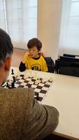Clever junior school age boy playing chess with dad planning gambit moving black piece on chessboard. Preteen son engaged in brain developing activity enjoy board game with father photo