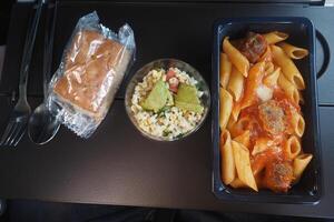 Lunch served during a flight with pasta and salad on a tray photo