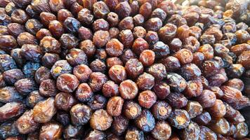 Fresh dates piled high at a market in a sunny location photo