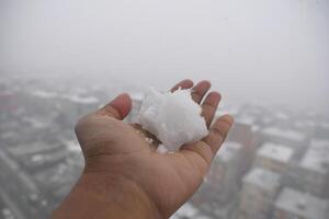 Snow held in a hand against a foggy city backdrop photo