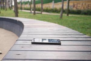 Phone forgotten on a wooden bench in a peaceful park setting photo