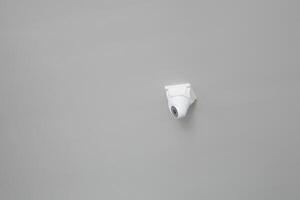 Security camera mounted on a plain gray wall for surveillance photo