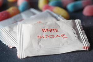 Sugar packets and colorful candy scattered on a table photo