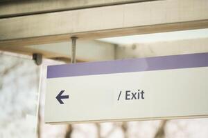 Sign pointing left toward exit in a public space photo