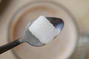 Sugar cube balanced on a spoon over coffee cup in a cozy setting photo