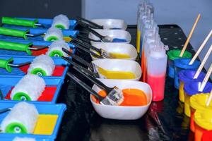 A table with many colorful paint brushes and paint photo