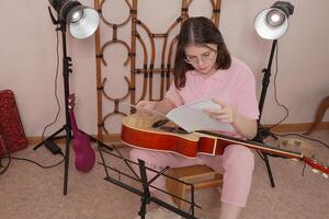 Guitarist with guitar methodically selects notes and studies them before commencing practice session photo