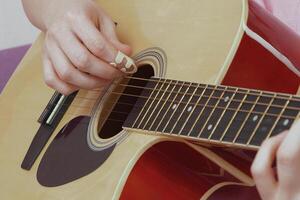 Close-up view of female guitarist is performing captivating solo, deftly manipulating fingers over frets and neck of acoustic guitar. This performance, executed in strumming style with guitar pick photo
