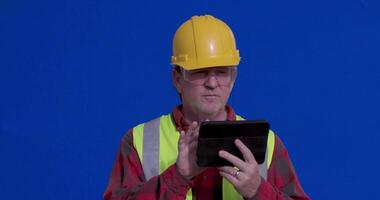 Chroma Key Blue Screen of Male Contractor Wearing Full PPE Using Computer Tablet While Overlooking Project. video