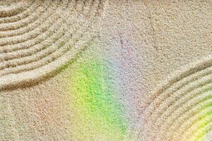 Smooth simple Lines on sand background, minimal aesthetic sandy texture with sunlight rainbow flare. Spa, meditation, relaxation, wellness concept. Natural beige waves pattern in Japanese zen garden photo