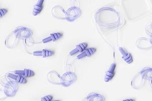 Violet purple color earplugs as minimal trend pattern on white, reusable silicone, rubber ear plug in box against noise, protect hear, for swim, sleep, rest. Creative aesthetic flat lay, photo