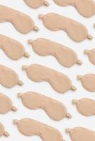 Trendy Minimal pattern from beige sleep masks on white background, above view. Neutral colored fashion cloth eye masks for best sleeper, for rest. Night time and sleep concept, flat lay photo