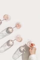 Rose wine glasses Minimal style above view. Aesthetic still life photo, woman's hand take wineglass, sun shadow, Concept of taste, alcohol, wine degustation, home ralahation. Flat lay copyspace photo