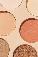 Close up minimal pattern with colorful eyeshadow samples, trend color swatches on beige background. Eyeshadows powder with glitters for makeup, shiny and matte, aesthetic photo, top view photo
