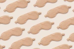 Trendy Minimal pattern from beige sleep masks on beige background, above view. Neutral colored stylish cloth eye masks for best sleeper, for travel, rest. Night time and sleep concept photo