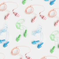Creative flat lay from colored silicone earplugs for swim, sleep, rest on white background. Comfort ear plug on string against noise, protect hear, aesthetic top view, visual trends photo