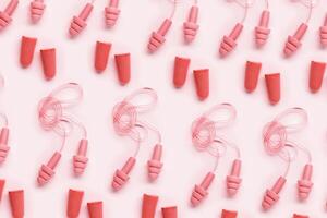 Colored earplugs as minimal pattern, reusable silicone and rubber ear plug on cord against noise, protect hear, for swim, sleep, rest. Creative aesthetic flat lay, above view, pastel tones photo