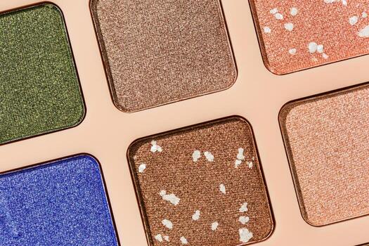 Top view texture pattern with different eye shadow swatches, multi colors palette in beige plastic package. Close up eyeshadows powder for makeup, cosmetics texture design, beauty background photo