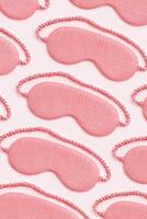 Minimal style pattern from pink sleep masks on pink background. Trend Colored fashion eye masks for best sleeper, for travel, comfort rest. Night time and sleep concept, vertical flat lay photo