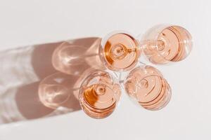Rose wine glasses Minimal style above view, peach fuzz trend color. Holiday aesthetic still life photo, top view wineglass at natural light, sun shadows, pink pastel color, simple drink background photo