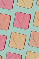Minimal pattern compact eye shadow glitter swatches on trend green background, pastel color photo, eyeshadow with heart imprint, beige pink colored powder makeup, square pack, cosmetic texture photo