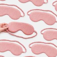 Minimal trend pattern from pink textile sleep masks on white light background. Woman hand take eye mask, comfort rest and quality sleep concept. Creative aesthetic top view composition photo