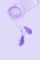 Close up reusable silicone earplugs purple color, for swim, sleep, rest. Soft, flexible ear plug in case against noise, protect hear, minimal style aesthetic monochrome background, top view photo