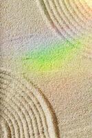 Top view pattern in Japanese Zen Garden with close up lines on sand, meditation and relaxation vibes. Aesthetic minimal sandy background with colorful rainbow reflections, beige monochrome color photo