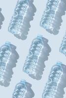 Minimal Pattern Plastic bottles water at sunlight with shadow on blue, aesthetic top view. Distilled drinking water. Pollution, environment protection. Eco trend to reduce disposable plastics photo