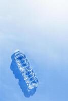 Plastic bottle water at sunlight with beautiful sun shadow on blue color background, copy space. Clean drinking water in bottle. Pollution, environmental protection concept. World water problem photo