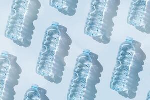 Minimal Pattern Plastic bottles water at sunlight with shadow on blue, aesthetic top view. Distilled drinking water. Pollution, environmental protection. Eco trend to reduce disposable plastic photo