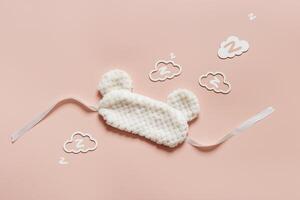 Sleep mask from soft nice fur and clouds shape with zz snore sounds on pink background. Light Fluffy eye cover mask for best sleep. Concept of travel comfort, dream well, rest at night, Minimal photo
