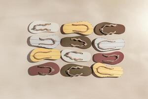 Summer flip flops flat lay, minimal square pattern, set of beach footwear neutral colored, top view still life with womans slide sandals, many shoes, summer beach holiday concept, shadow from sunlight photo