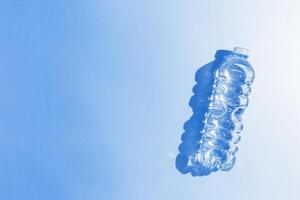 Plastic bottle water at sunlight with shadow, sun glare on blue background, aesthetic top view. Distilled drinking water. Pollution, environmental protection. reduce disposable plastics photo