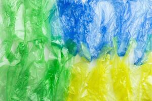 Plastic bags texture, top view crumpled plastic bag crumpled, green blue yellow colored textured background. Surface from Disposable polythene packet. Reusable materials, packaging waste photo