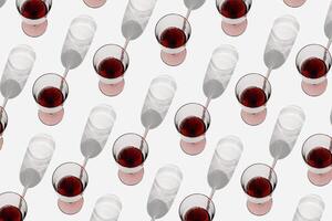 Minimal summer pattern with glasses of red wine, sunlight shadow on white background. Wine glasses flat lay, alcohol drinks modern photo. Holidays, parties, events, relaxation concept. Top view photo