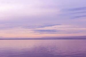 Minimal Colorful sky background on sunset, purple pastel color clouds and surface water on lake Ik. Nature abstract composition with reflections on water, natural blue pink shades of skyline photo