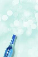 Aesthetic Top view sparkling wine, blue bottle of wine with sunlight flare, bokeh on turquoise background, Happy holidays summer monochrome card, Festive summer party alcohol drink concept photo