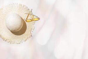 Top view summer sun hat and yellow glasses at sunlight on pastel beige background with blurred bokeh as copy space. Life style fashion summer vacation concept photo, minimal style flat lay photo