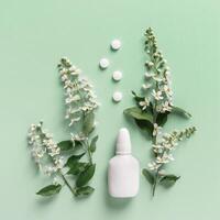 Seasonal spring allergies, fresh spring blooming branches tree and mock up white nasal spray bottle, pills on green background, top view, minimal flat lay Seasonal allergy treatment concept. photo