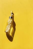 Glass bottle with lemon water drink detox at sunlight on yellow background, copy space. Healthy infused water boost metabolism and weight loss. Aesthetic still life minimal, summer drinks photo