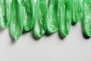Minimal pattern from green disposable plastic bags on white Waste reduction, Environmentally friendly, recycling concept. Pollution from Polyethylene packets, plastic bag free day. photo
