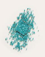 Crushed eye shadow powder cosmetics swatch trend colored teal. Makeup powder texture vertical photo. Broken eye shadow smear. Aesthetic minimal style flat lay, face cosmetic product sample photo