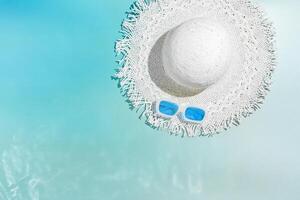 summer minimal life style background, top view white sun hat on blue with sun glare photo