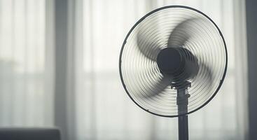 A Modern Stand Fan Circulating Air in a Bright Room Near Sheer Curtains photo