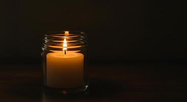 A Single Lit Candle in a Glass Jar Illuminating the Darkness photo